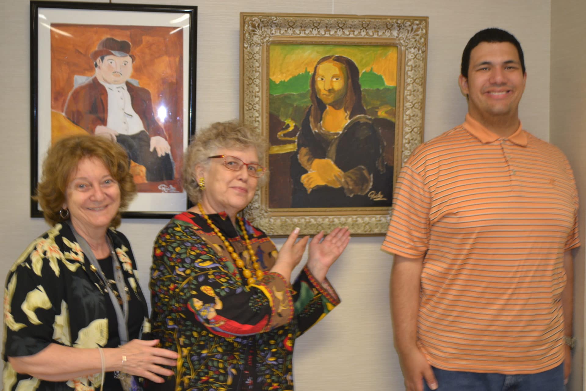 An artist from the AHRC Nassau East Meadow Art Gallery proudly stands in front of his painting at the East Meadow Public Library