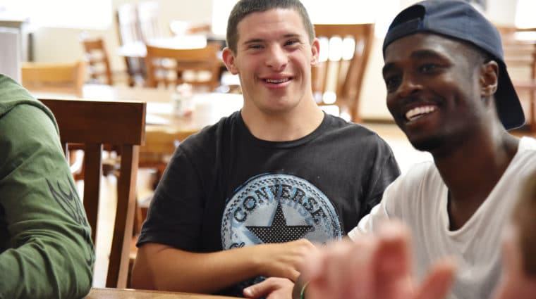 A person with developmental disabilities enjoying a group activity smiles.