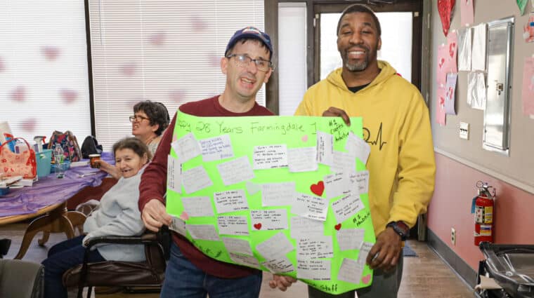 Residents of Farmingdale 1 hold up a sign they made for their anniversary celebration.