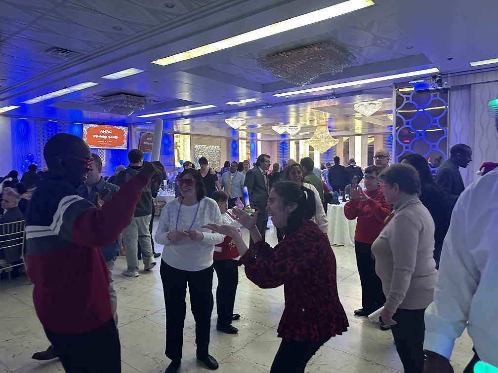 People supported by AHRC Nassau Residential Services dance on the dance floor at their holiday party