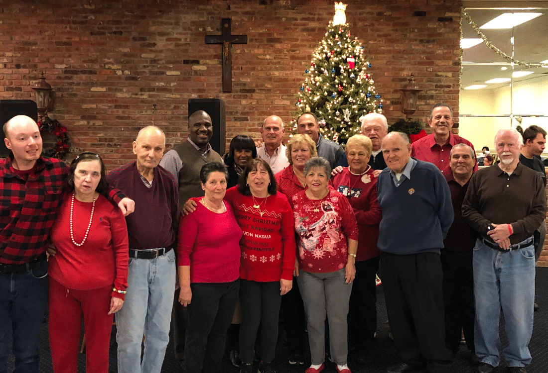 Guests of the Annual Knights of Columbus holiday party gather around the Christmas tree for a photo