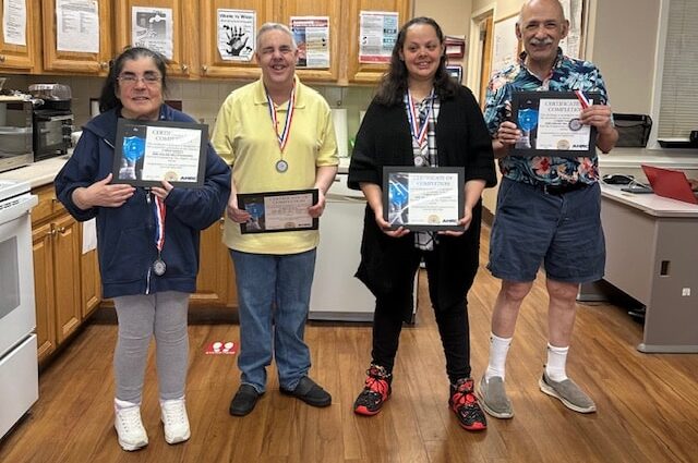 People supported by AHRC NAssau Day Services show off their certificates