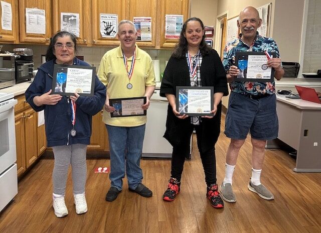 People supported by AHRC NAssau Day Services show off their certificates