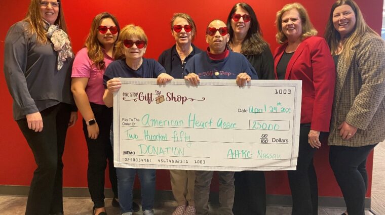 Interns at the One Stop Gift Shop hold a giant check for $25,000 for the American Heart Association