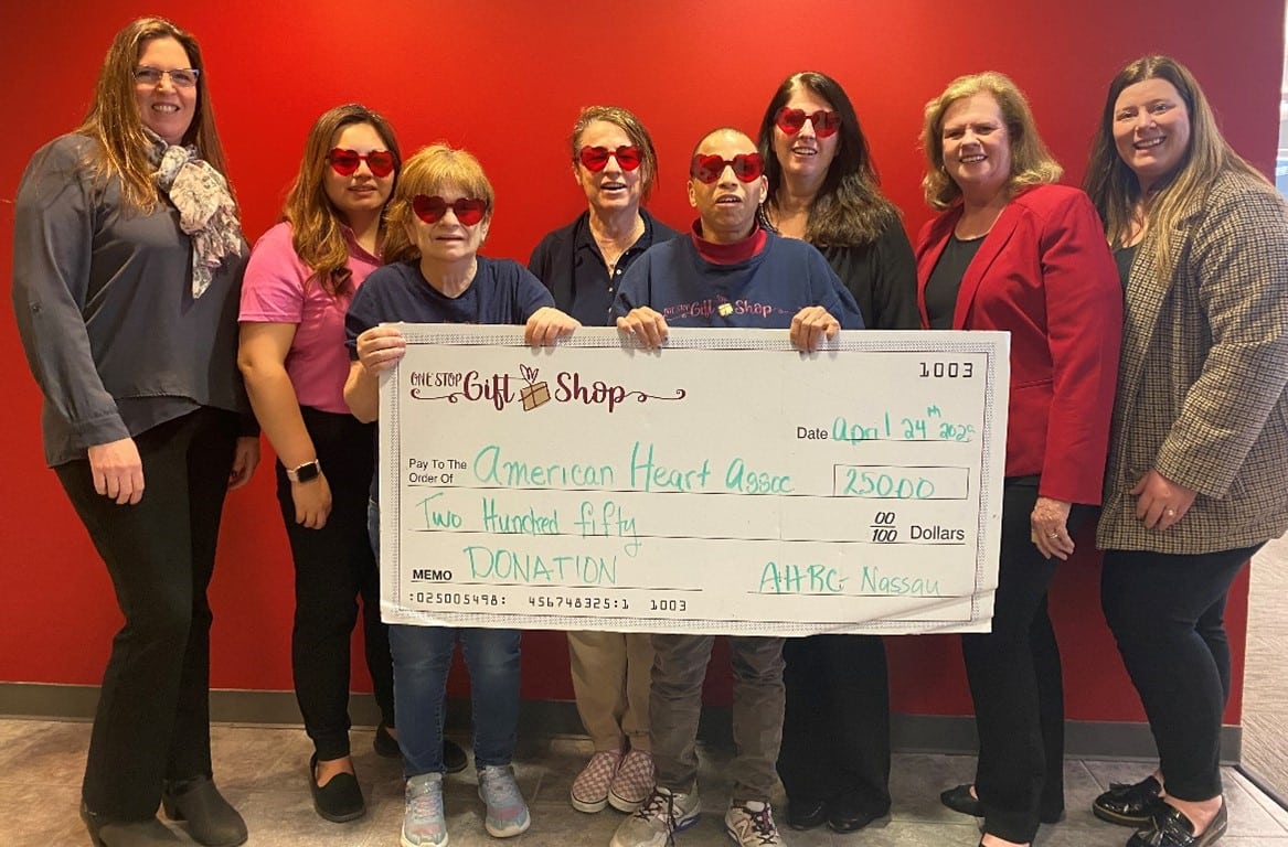Interns at the One Stop Gift Shop hold a giant check for $25,000 for the American Heart Association