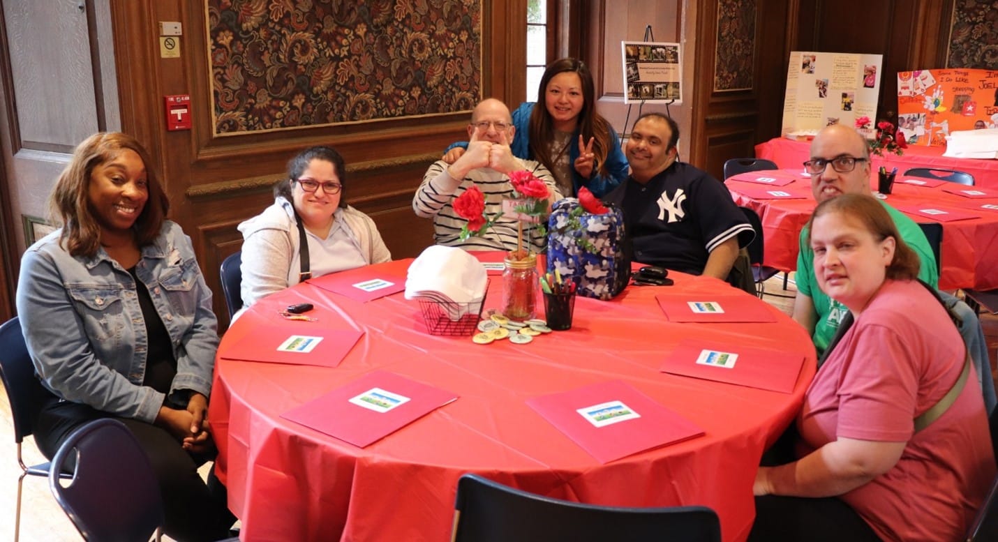 People supported gathered around a table at the POMs Rally.