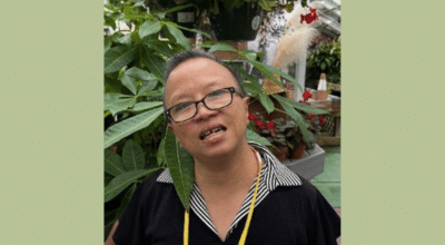 Tracey Zhang in front of green plants at her job Wheatley Farms