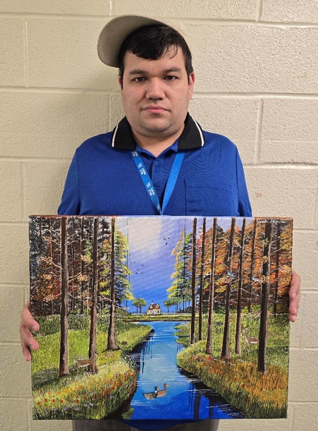 Wenceslao Herrera holds up his painting of trees with a river running through them.