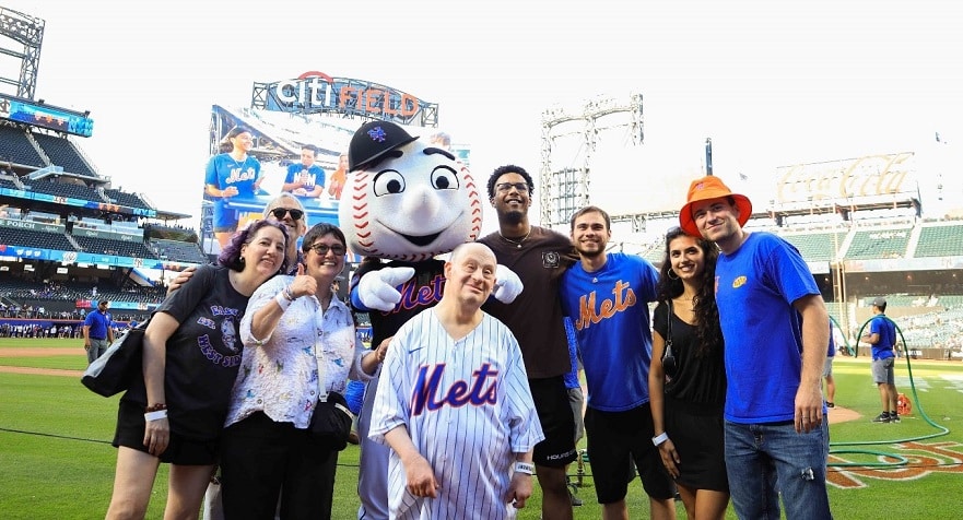 Adam Levine and his family take a photo with Mr. Met on the field at the Mets game.