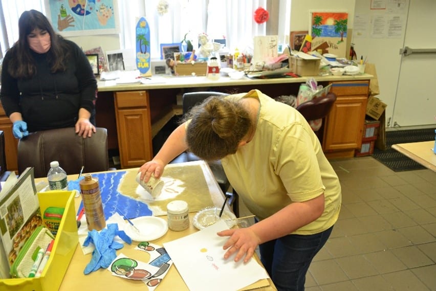 An artist creates beach-themed artwork at East Meadow Art Gallery