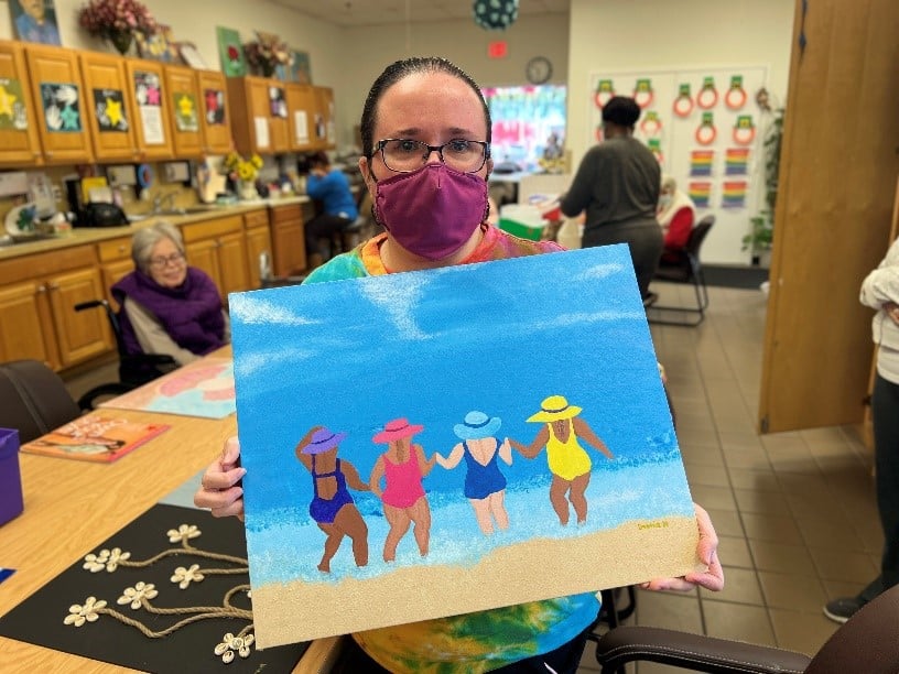 An artist shows off her painting at the East Meadow Art Gallery