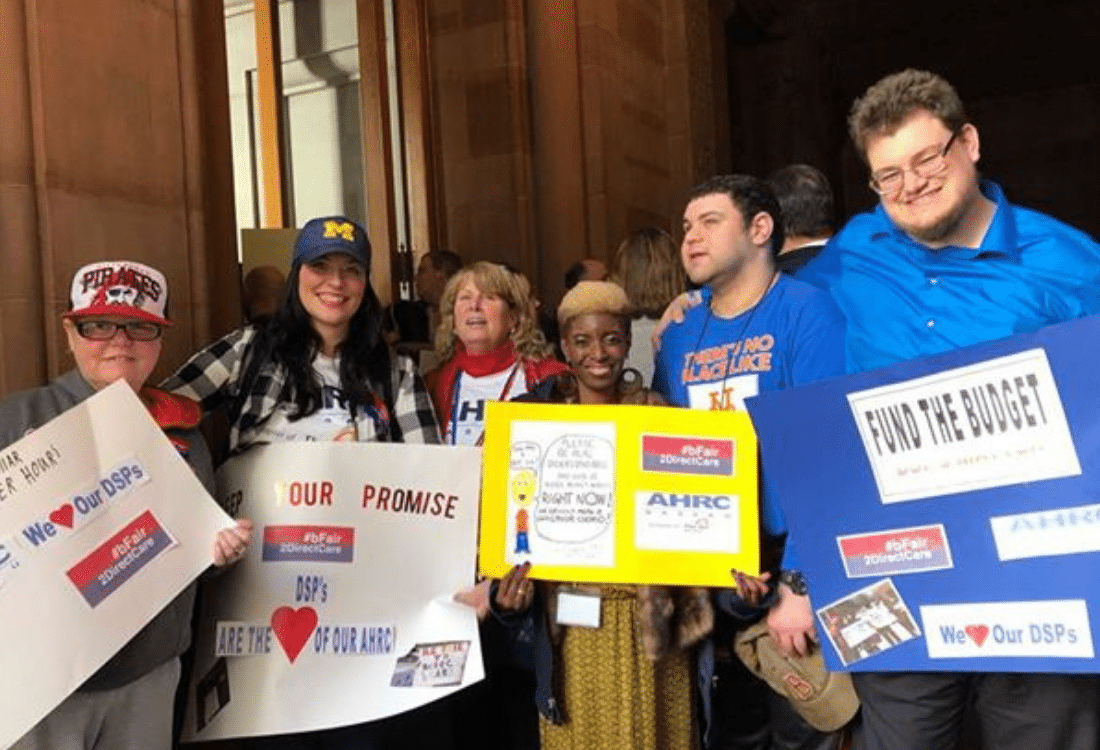 Group of self-advocates smile in Albany while rallying for #bFair2DirectCare