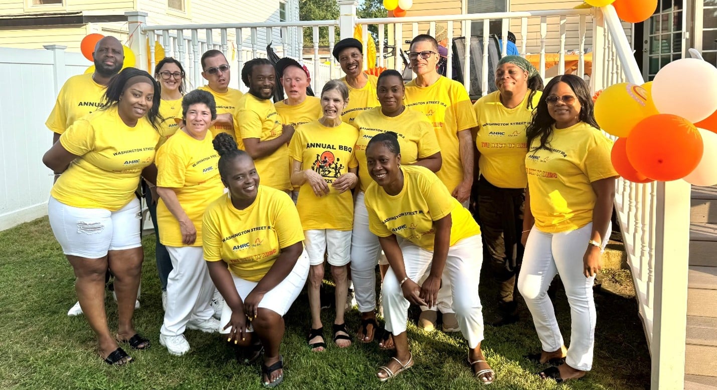 Staff members and residents at Washington Street pose in matching shirts worn at their annual summer barbecue.