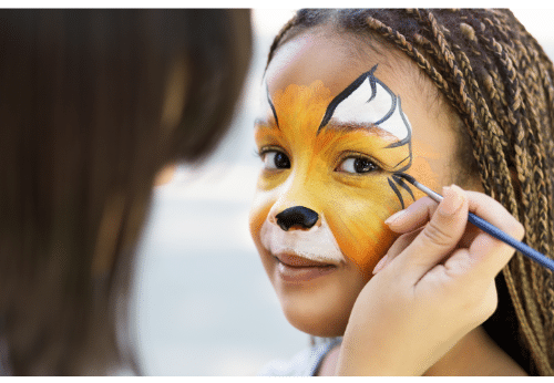Girl gets her face painted as a tiger