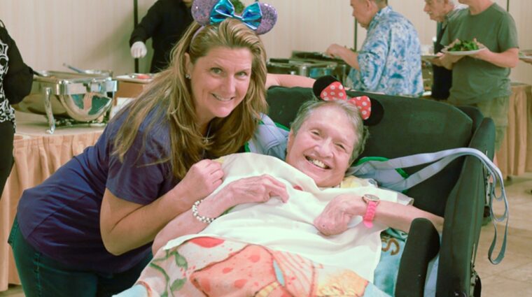 A person supported by AHRC Nassau's Guardianship Services and a staff member pose for a photo wearing Mickey ears.