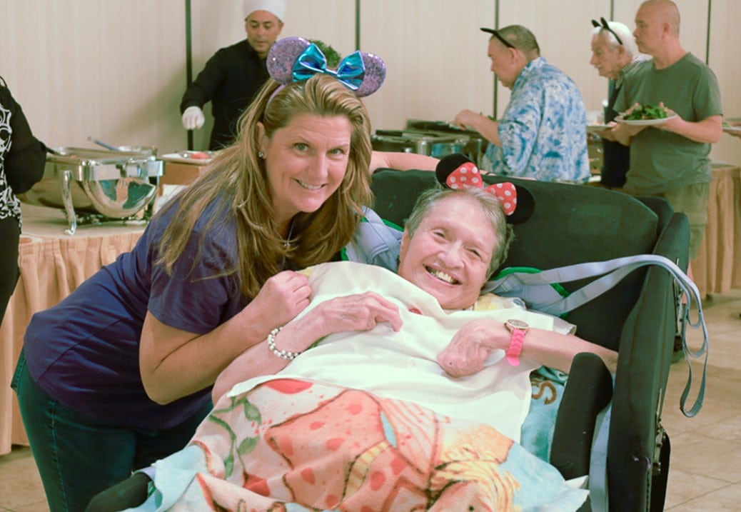 A person supported by AHRC Nassau's Guardianship Services and a staff member pose for a photo wearing Mickey ears.