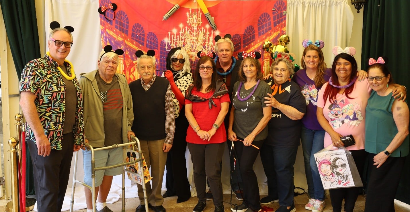 Attendees of the Guardianship party pose with Mickey Ears in front of a Disney-themed backdrop.