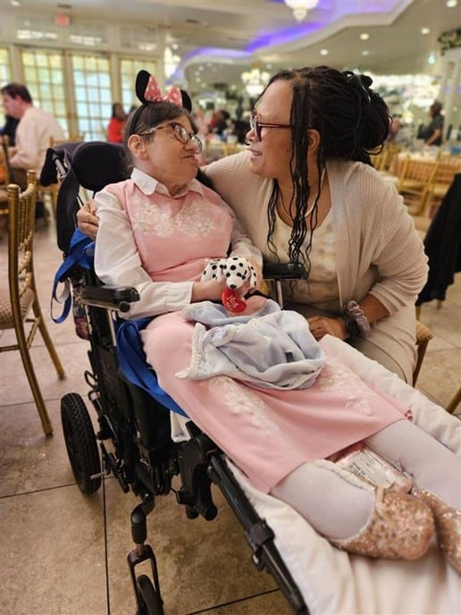 A person supported by AHRC Nassau's Guardianship Services and a staff member enjoy the guardianship party.