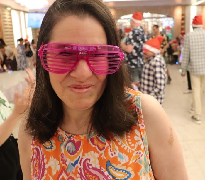 A person supported by AHRC Nassau wears pink shutter glasses at the holiday party.