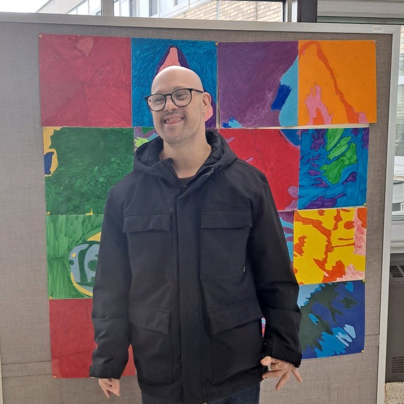 An AHRC Nassau poses in front of his artwork.