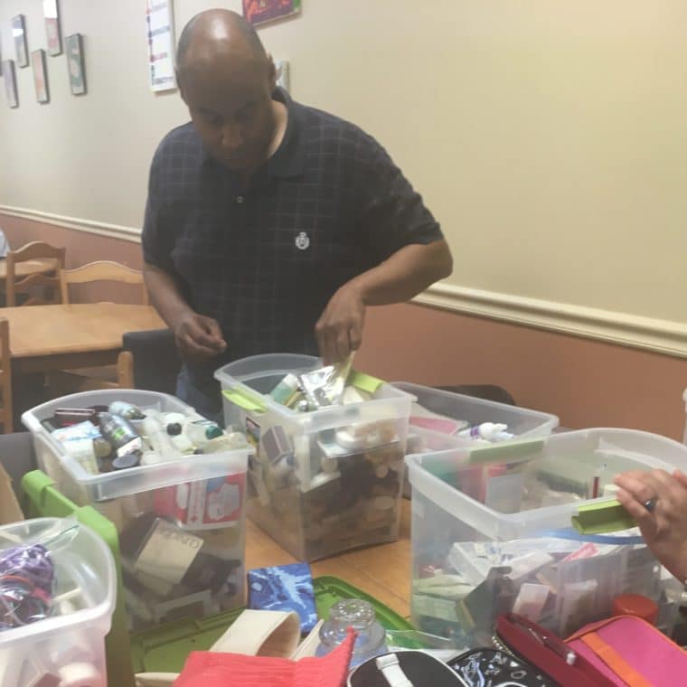 An AHRC Nassau volunteer helps fold and pack items for baskets donated to MOMMAS House.