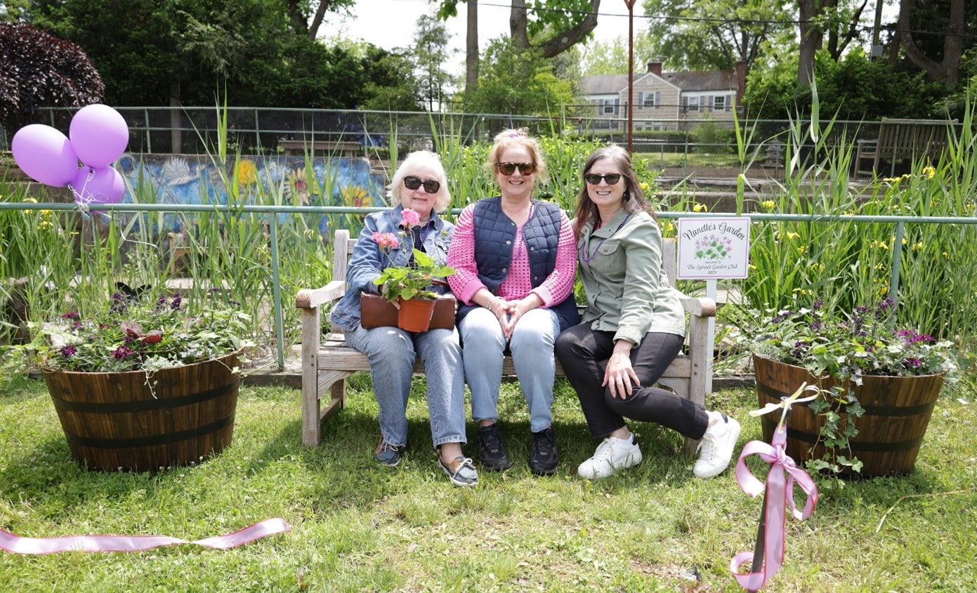 AHRC staff members sit on a bench in Nanette's Garden