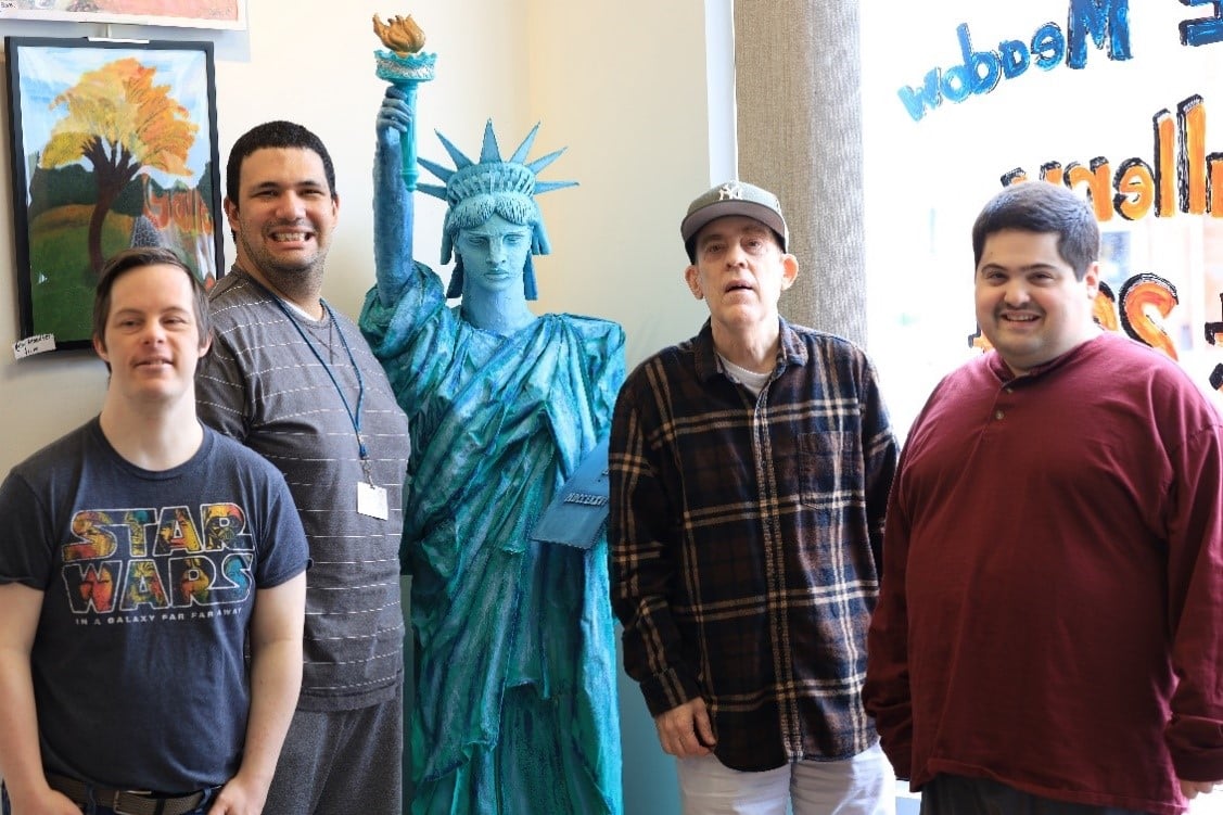AHRC East Meadow Art Gallery artists pose with a Statue of Liberty sculpture