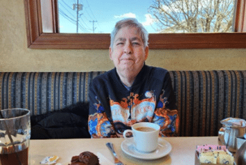 A person supported by AHRC Nassau's guardianship program sits in a diner booth with a cup of coffee.