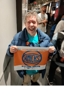 A person supported by AHRC Nassau's guardianship program  holds up a Knicks flag.