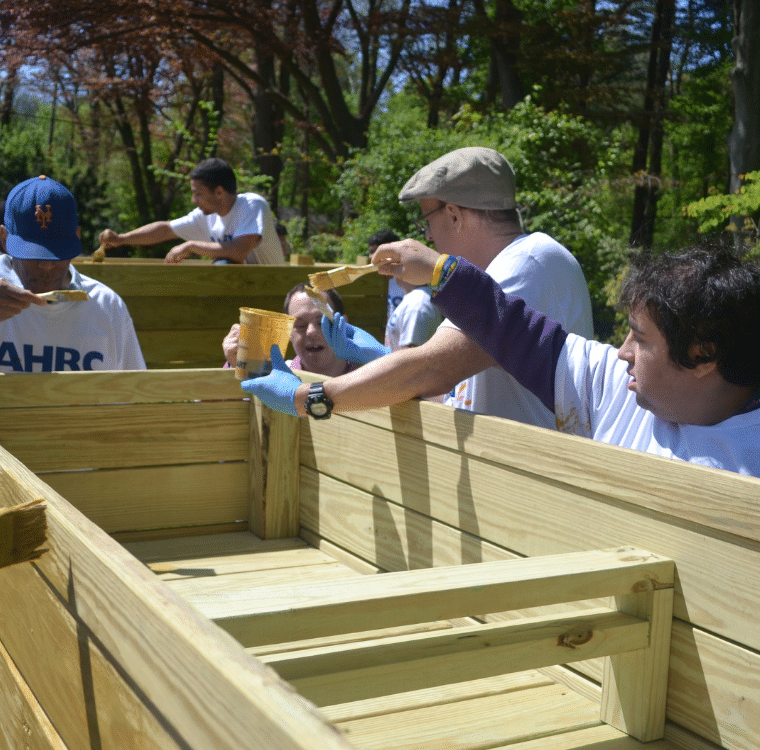 Nassau BOCES students and AHRC Nassau Day Hab participants add finish to a wooden planter.