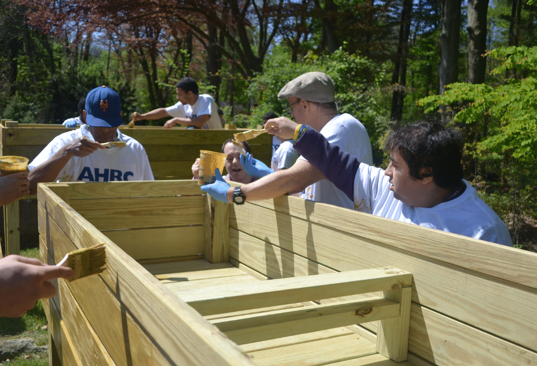 Nassau BOCES students and AHRC Nassau Day Hab participants add finish to a wooden planter.