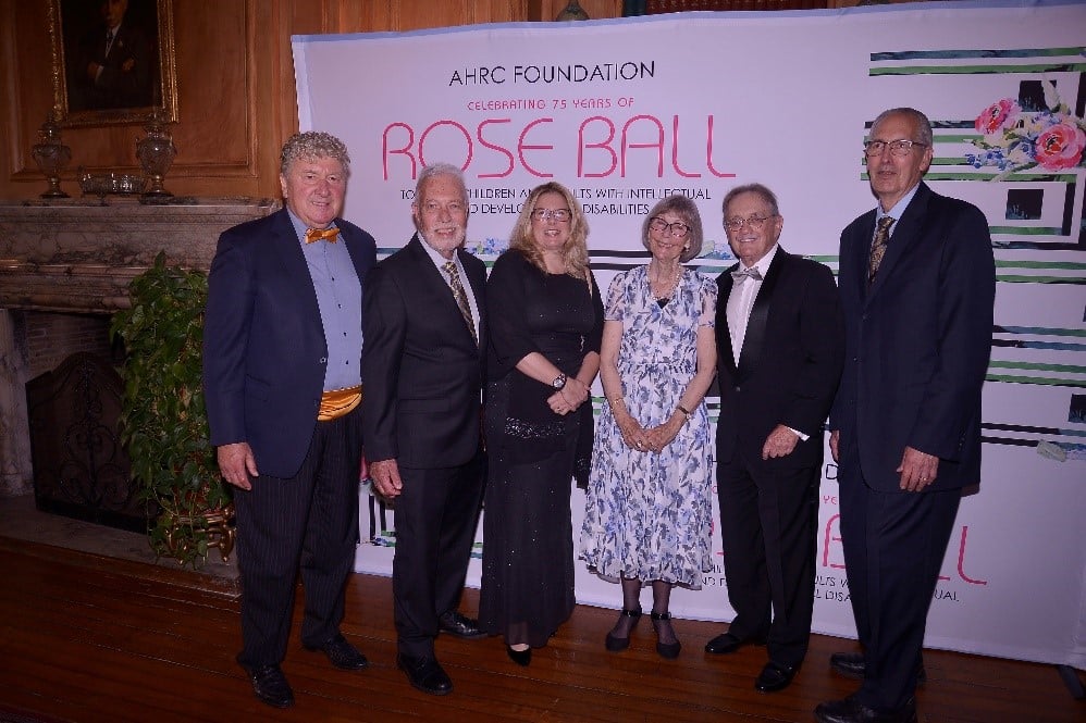 Attendees of the 75th Annual Rose Ball pose in front of the Step and Repeat