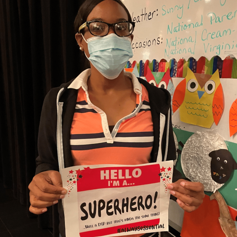 Irlande Elius, DSP, holds a sign celebrating DSP Week and her role as a superhero.