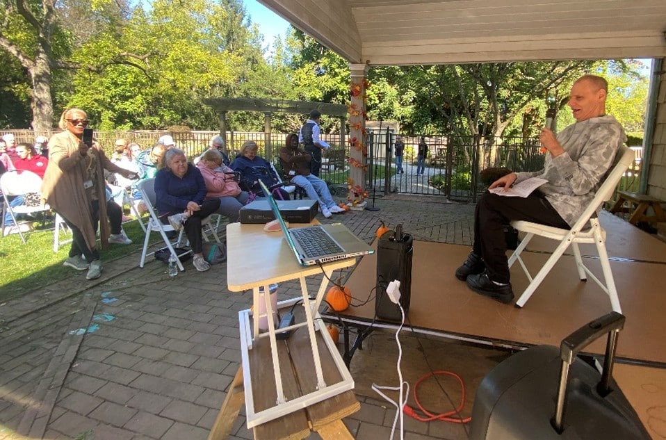 A person supported by AHRC Nassau performs on stage in front of an audience at the talent show.