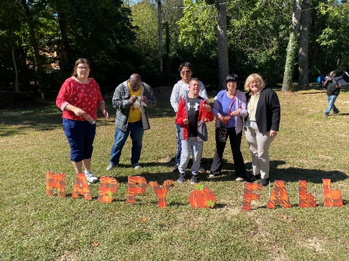 Five people supported by AHRC Nassau stand behind a sign that reads "Happy Fall"