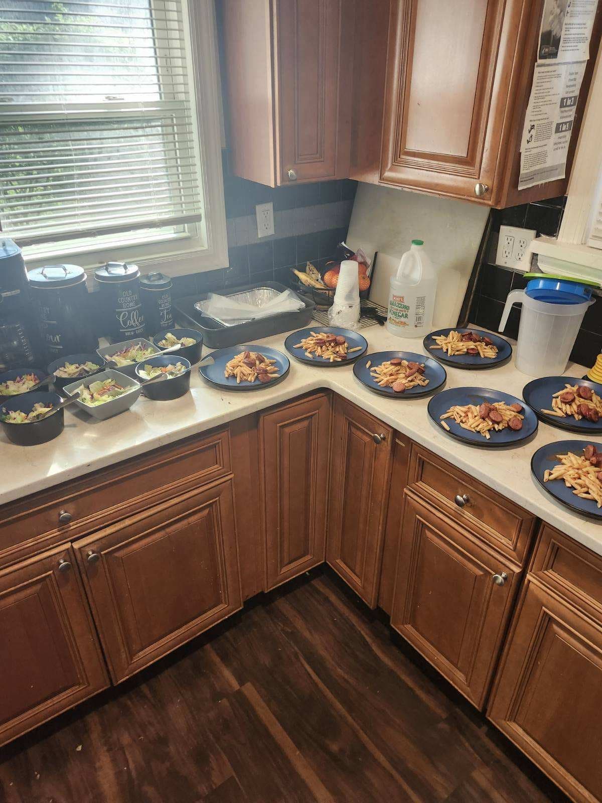Plates of pasta, sausage, and salad cooked by Timothy 