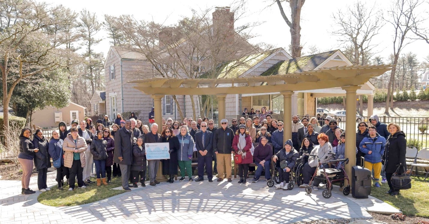 Assemblyman Charles Lavine, AHRC Nassau staff members, and local community members pose for a photo in the new Wheatley Farms d Arts Center meditation garden.